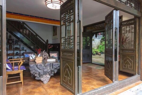 A traditional interior with a staircase, a reception desk, and decorative elements. - Qingcheng Mountain Yiyuanju Bieyuan Hostel (Dujiangyan)
