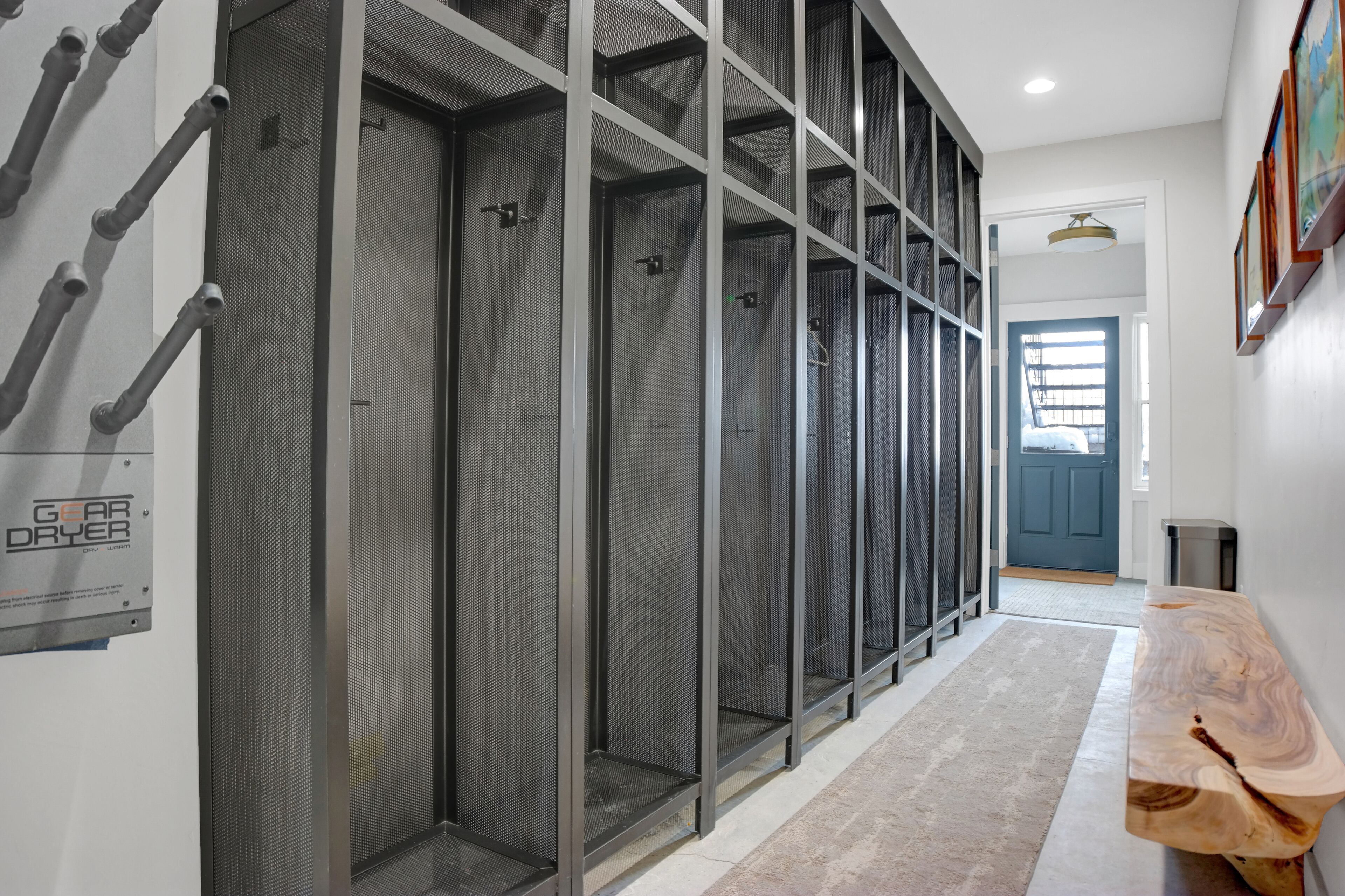 A hallway with a row of enclosed spaces, possibly utility rooms, and a wooden bench along the wall.