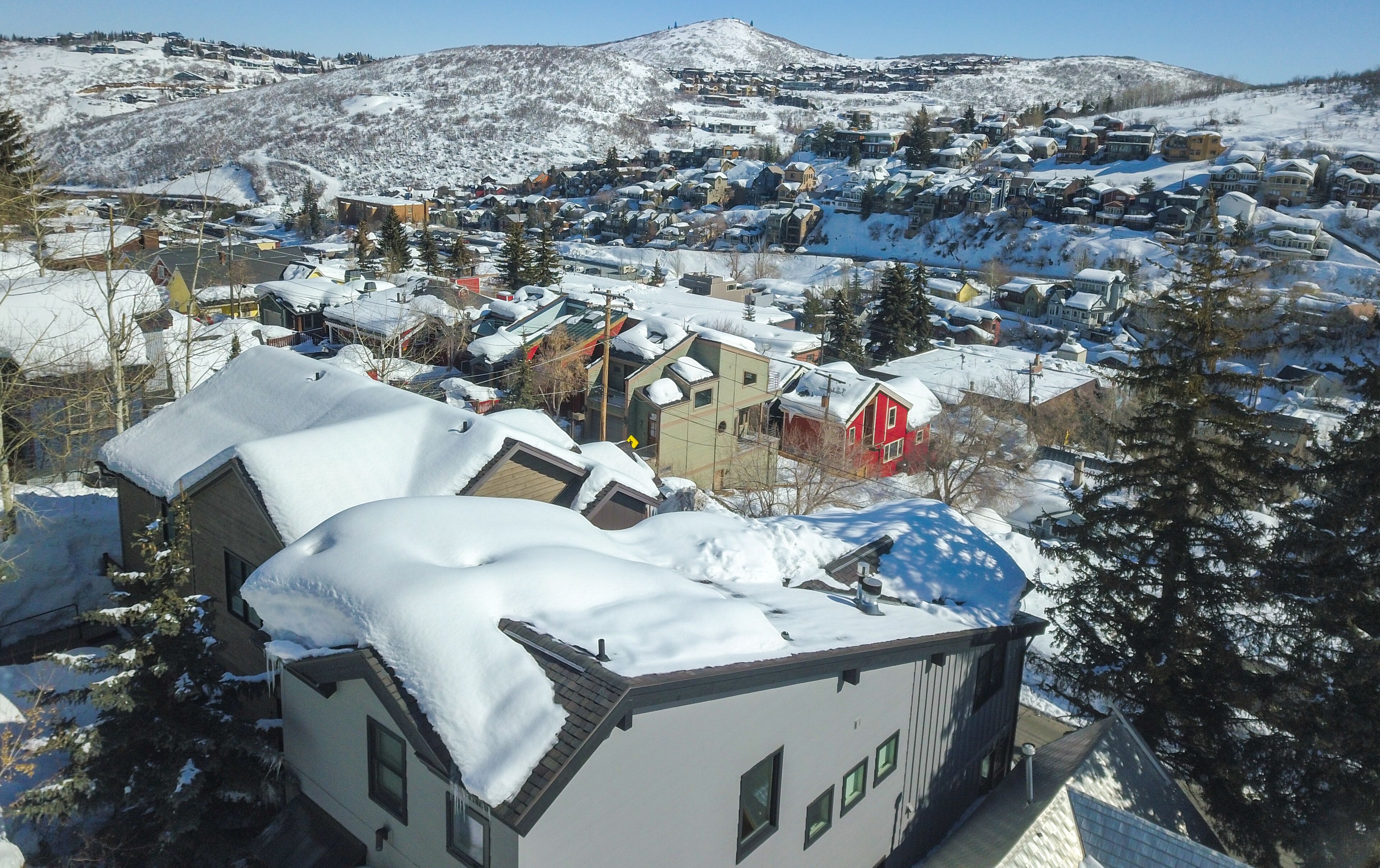 Una zona residencial cubierta de nieve, con casas y un edificio rojo destacado.