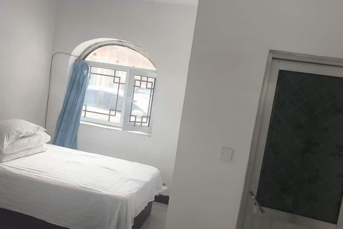 A bedroom with a bed, a window with a view, and a door.