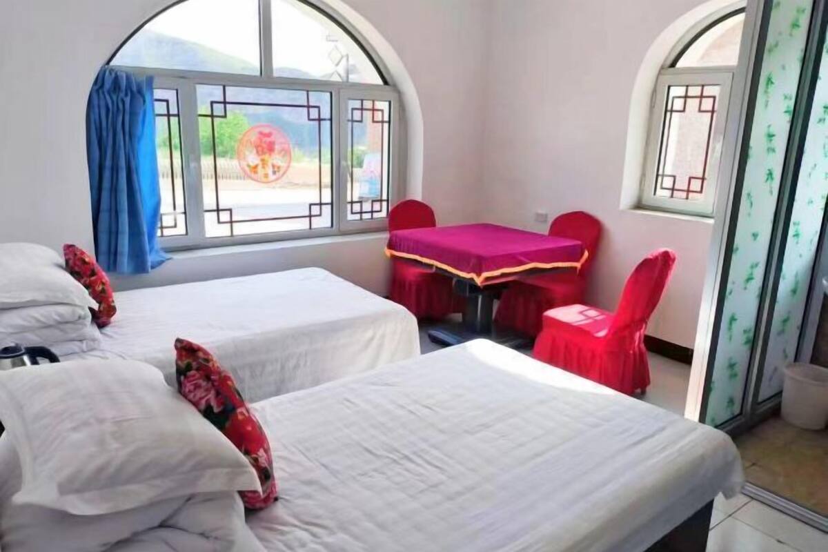 A room with two beds, a table with chairs, and a window with a view.