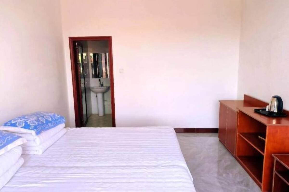 A bedroom with a bed, a wooden desk, and a mirror.