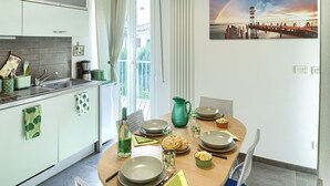 A modern kitchen with a dining area, featuring a round table set for two with plates, bowls, and cutlery.