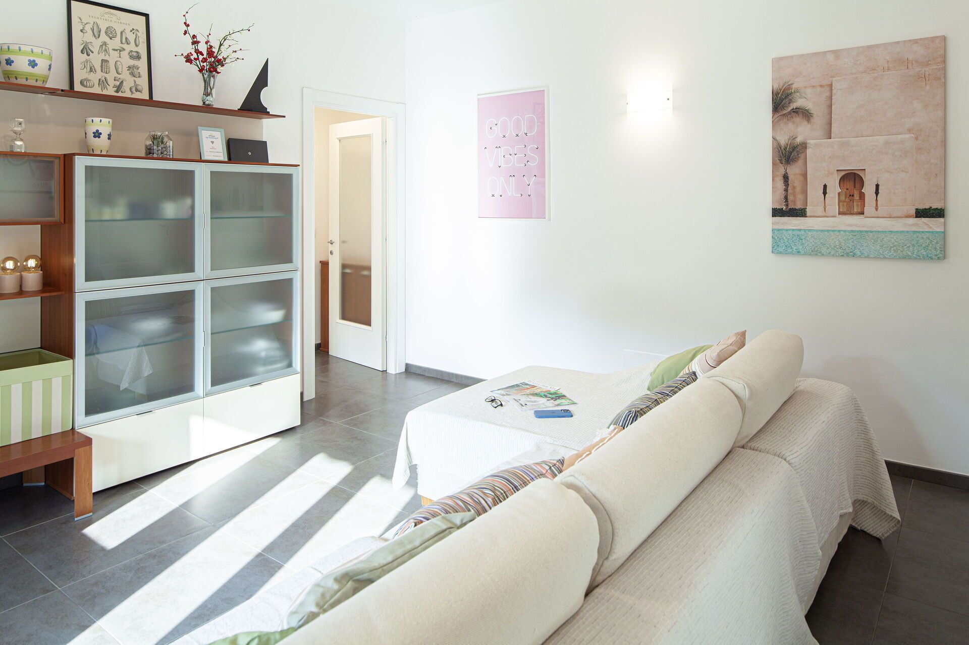 A modern hotel room with a sofa, a glass cabinet, and a painting on the wall.