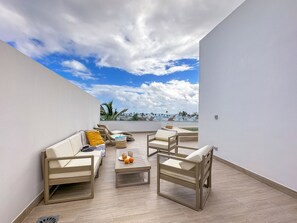 A rooftop terrace with a sofa, chairs, and a table, overlooking a coastal view. - Elegant and spacious Penthouse with Ocean View (Punta Cana)