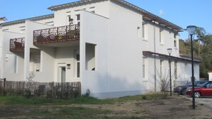 A two-story building with a balcony, a wooden fence, and a parked car. - Welcome at Sylvie's residence (La Tranche-sur-Mer)