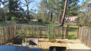 An outdoor patio with a table and chairs, surrounded by a wooden fence, with trees and a house in the background. - Welcome at Sylvie's residence (La Tranche-sur-Mer)