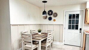 A dining area with a wooden table and chairs, a potted plant, and wall decor. - Casa Luna Blue Ridge Parkway (Arden)