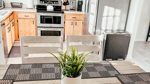A modern kitchen with wooden cabinets, stainless steel appliances, and a dining area with a table and chairs. - Casa Luna Blue Ridge Parkway (Arden)