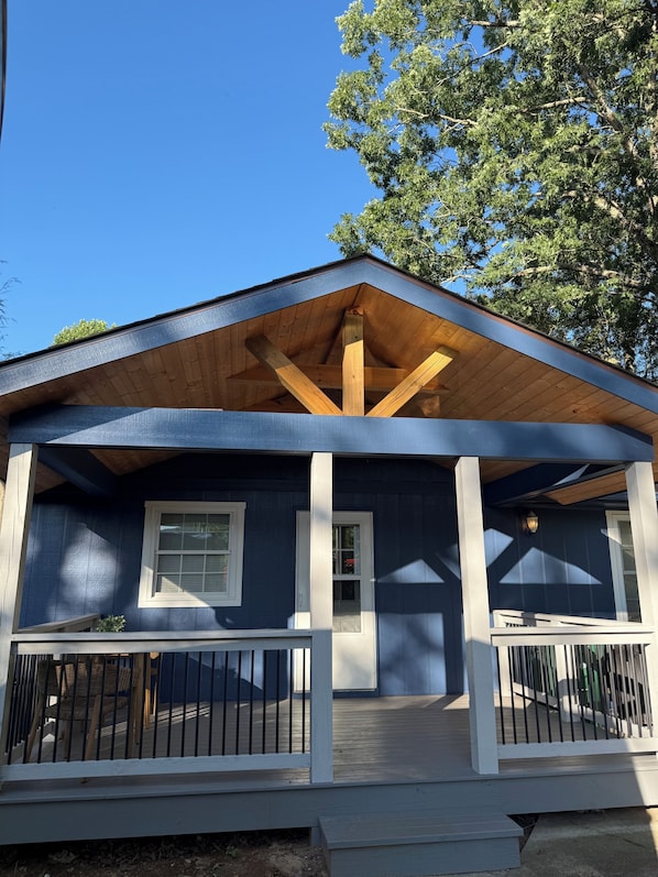 A two-story house with a covered porch, wooden beams, and a blue exterior.