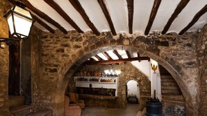 A stone-walled room with a vaulted ceiling, a fireplace, and shelves with pottery. - Mas d´en Tarres by Interhome (El Catllar)