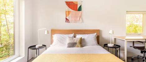 Una habitación de hotel con una cama grande, dos mesitas de noche, un escritorio y una silla.