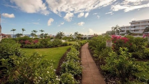A pathway through a landscaped garden with a clear sky and a sign indicating no smoking.