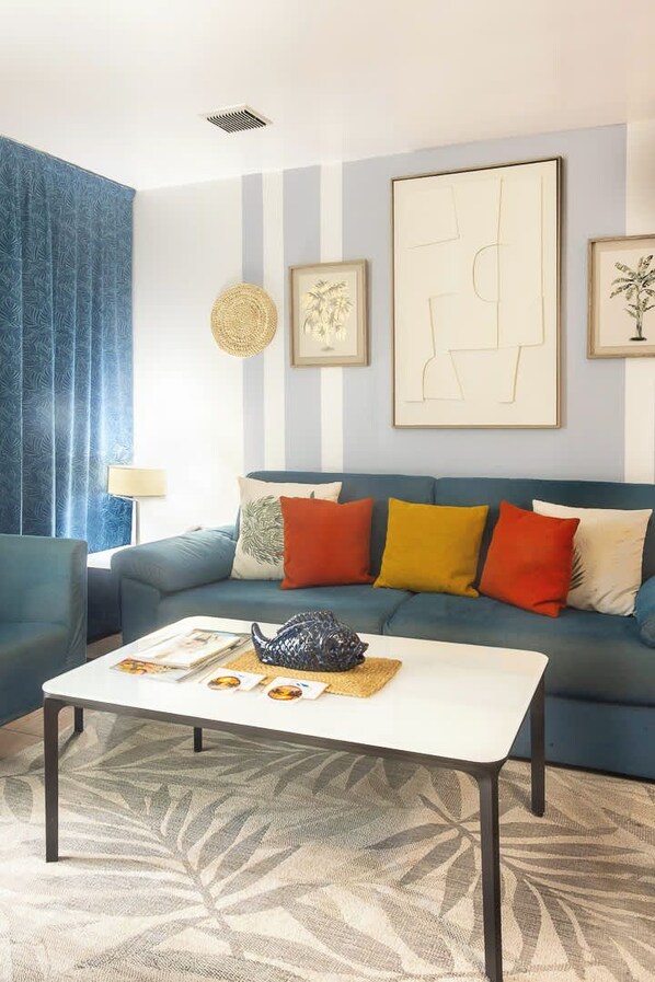 A living room with a blue sofa, a white coffee table, and a patterned rug.