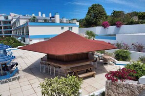 A rooftop patio with a wooden deck, outdoor seating, and a pool.
