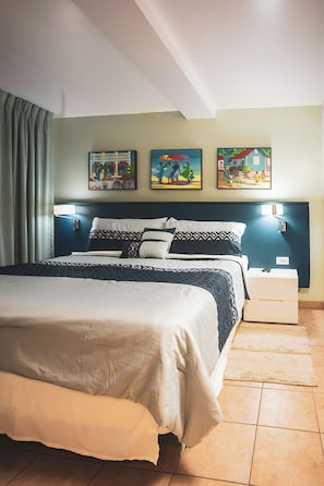 A hotel room with a bed, a nightstand, and three wall-mounted paintings.