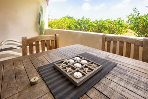 Una mesa de madera con un tapete, estrellas de mar y conchas marinas, frente a un balcón con vistas a la vegetación.