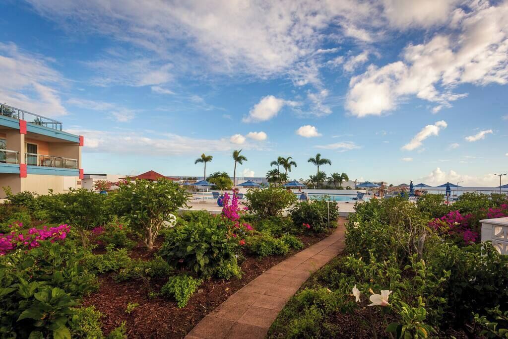 A resort with a pool area, palm trees, and a pathway lined with flowers.