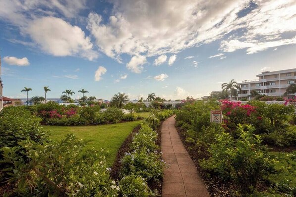 A pathway through a landscaped garden with a clear sky and a sign indicating no smoking. - Grand Getaway - Royal Retreats at Maho Beach Studio (Lowlands)