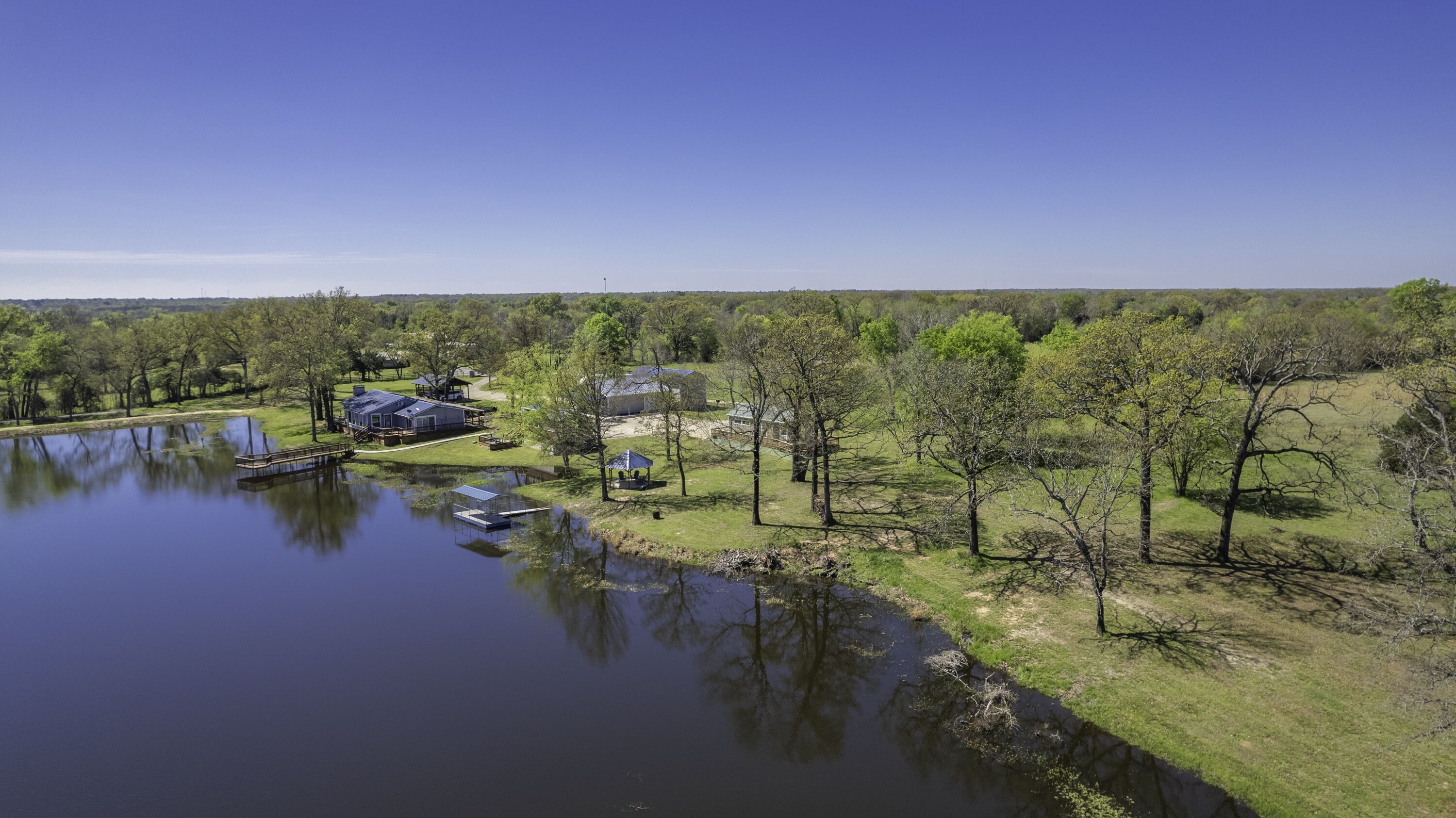 A lakeside property with multiple buildings, a dock, and a gazebo.