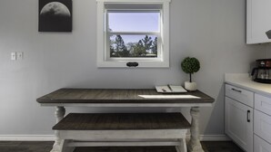 A kitchen with a wooden table, a window, a small potted plant, and a coffee maker. - SweetDove Stays-  Suite; w/ Stocked Lake, Secure Parking (Rains County)