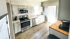 A kitchen with white cabinets, a stainless steel microwave, a stove, and a sink. - Fenced Yard - <1 mile from Purina - No Cleaning Fee (Gray)