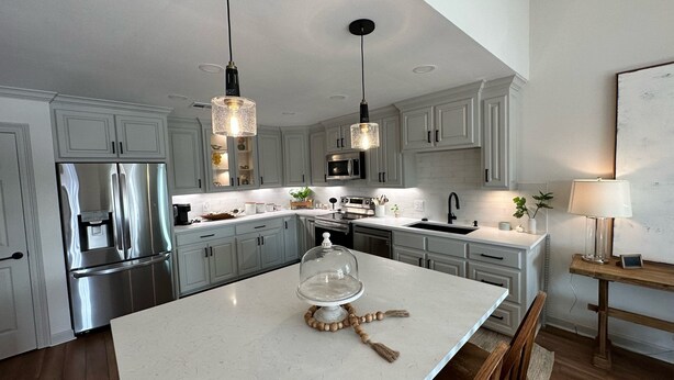 A modern kitchen with white cabinetry, stainless steel appliances, and pendant lighting.
