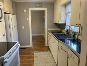 Kitchen area with central island, sink, and stove, featuring cabinetry and a wooden floor.