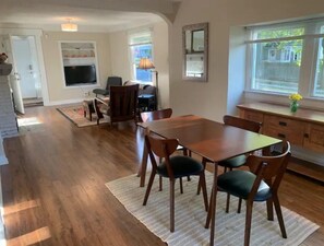 Enjoy meals in this dining area with a wooden table and six chairs, offering a view of the outdoors through the large window.