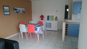 Un espacio habitable compacto con comedor, kitchenette y baño pequeño.