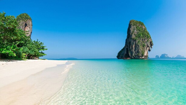 A beach with clear turquoise water, white sand, and a prominent rock formation. - Prague Bungalow Phu Quoc (Phu Quoc)