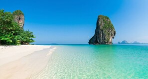 A beach with clear turquoise water, white sand, and a prominent rock formation. - Prague Bungalow Phu Quoc (Phu Quoc)