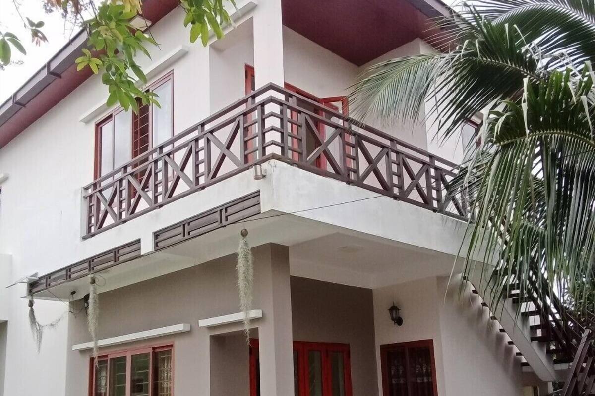 A two-story building with a balcony, red-framed windows, and a staircase leading to the upper floor.