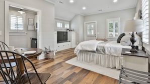 A bedroom with a bed, bedside table, lamp, and a window. - The Cottages at Laurel Brooke (Peachtree City)