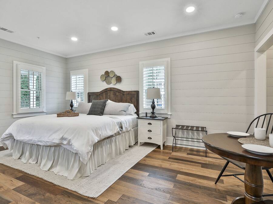 A bedroom with a bed, bedside tables, a chair, and a dining table.