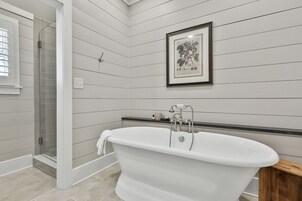 A bathroom with a freestanding bathtub, a shower enclosure, and a framed botanical print on the wall.