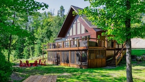 Een chalet met een houten terras en een ruime veranda met ramen.