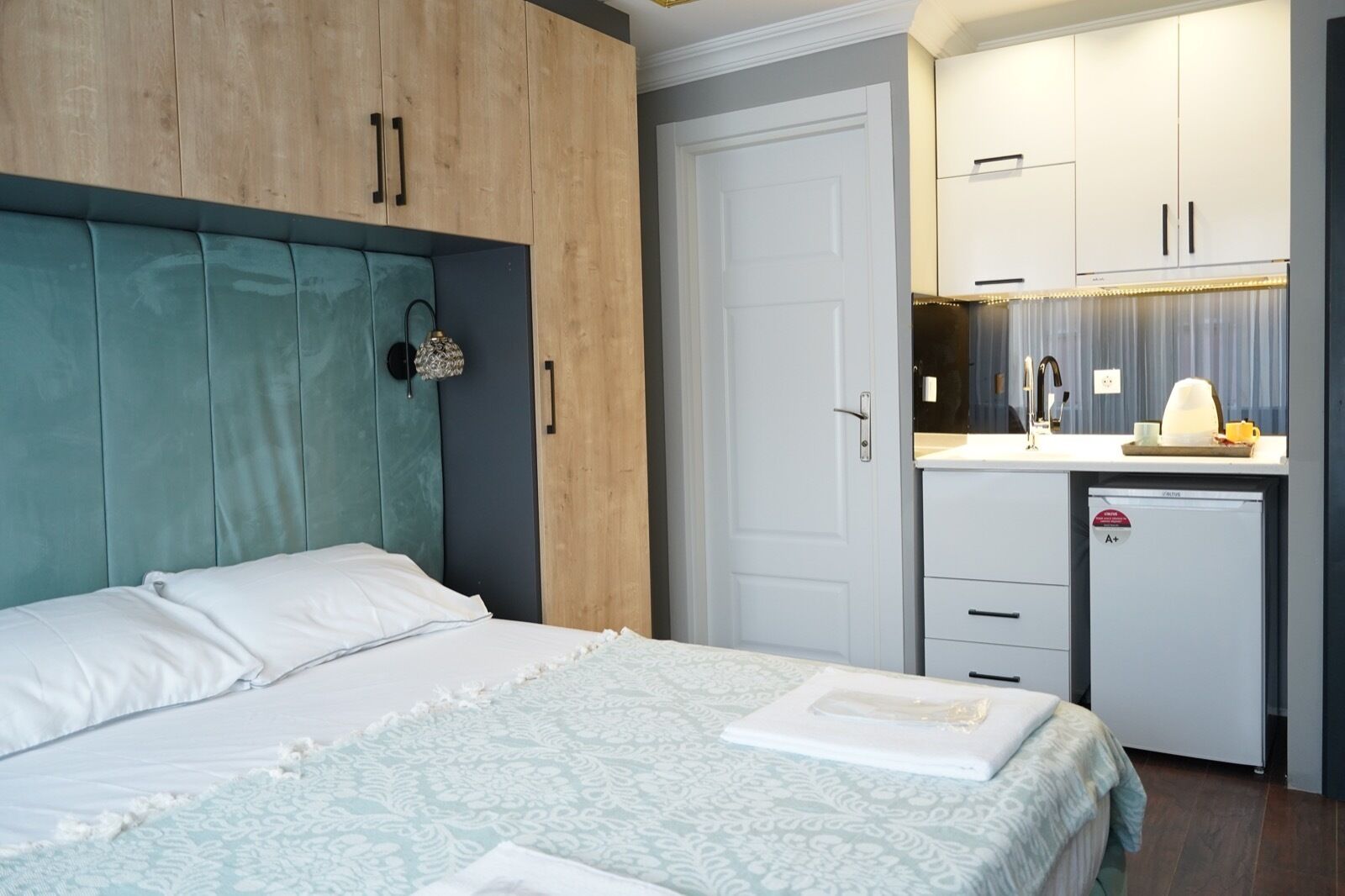 A bedroom with a bed, a wardrobe, and a kitchenette.