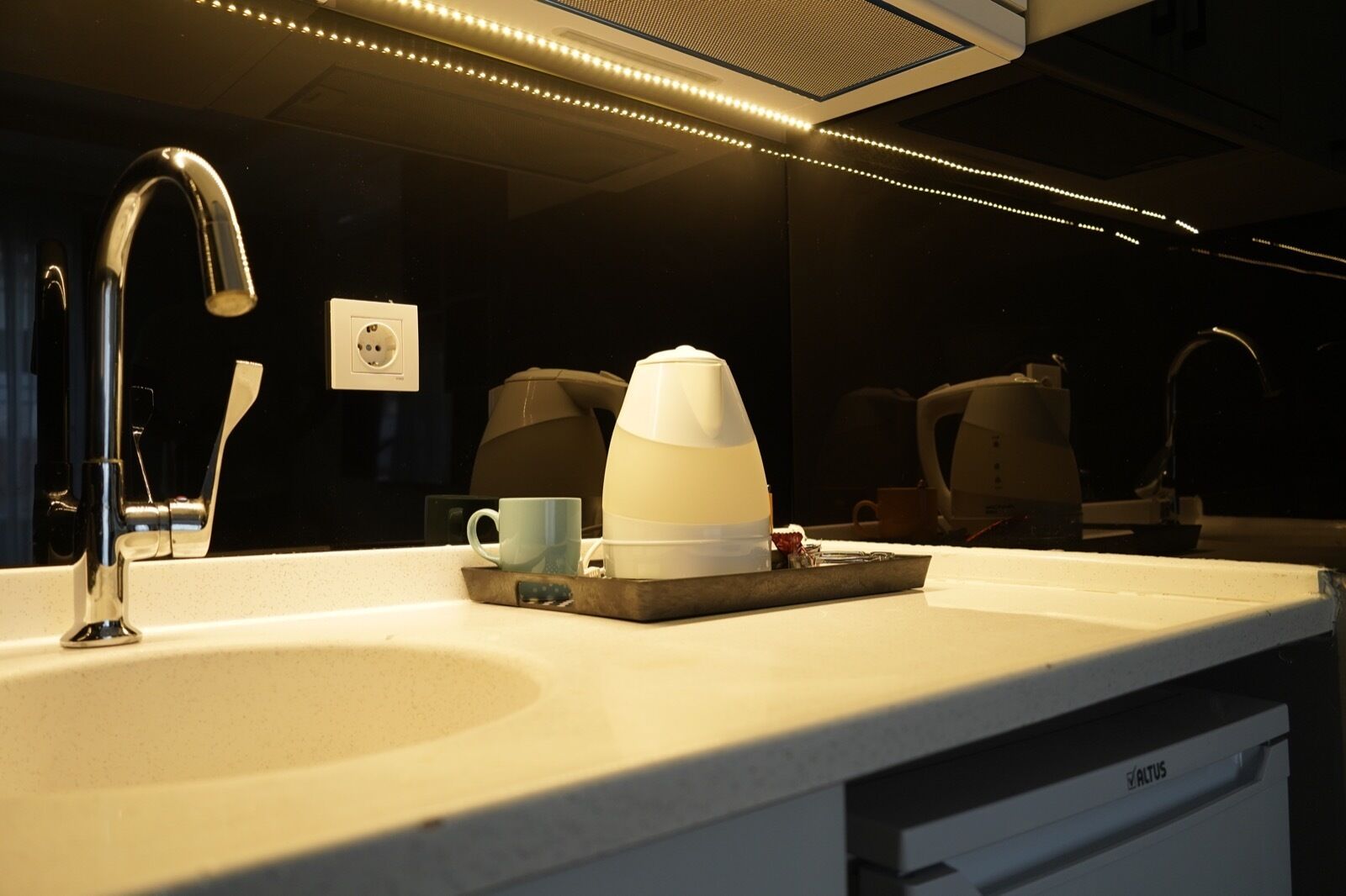 A modern bathroom with a sink, a coffee maker, and a cup.