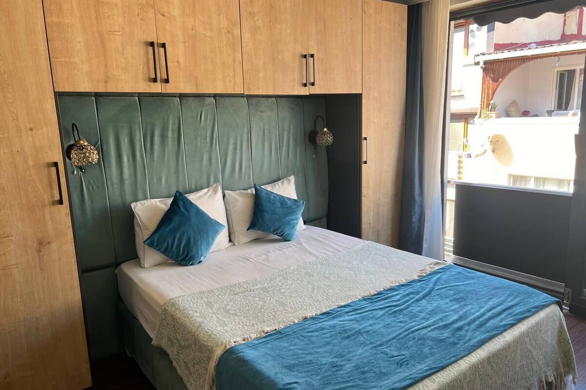 A bedroom with a bed, a headboard, and a window.