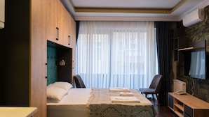 A compact hotel room with a bed, a desk, a chair, and a TV. -  Middle Village (Istanbul)