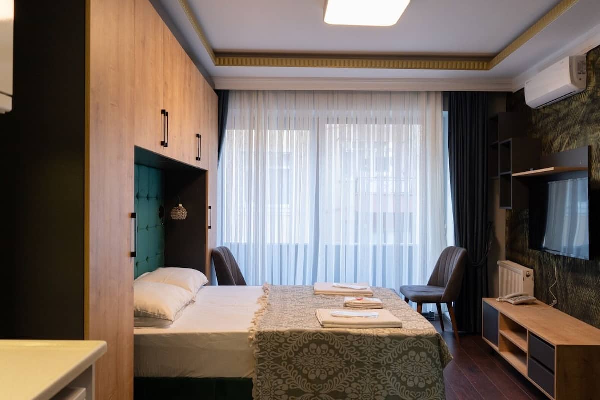 A compact hotel room with a bed, a desk, a chair, and a TV.