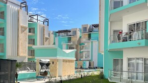 Un edificio moderno de varios pisos con piscina, zona de estar al aire libre y césped cuidado.