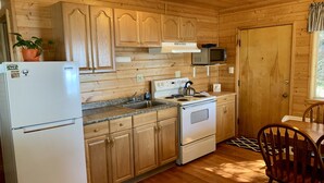 A wooden-paneled kitchen with a refrigerator, stove, microwave, and cabinets.