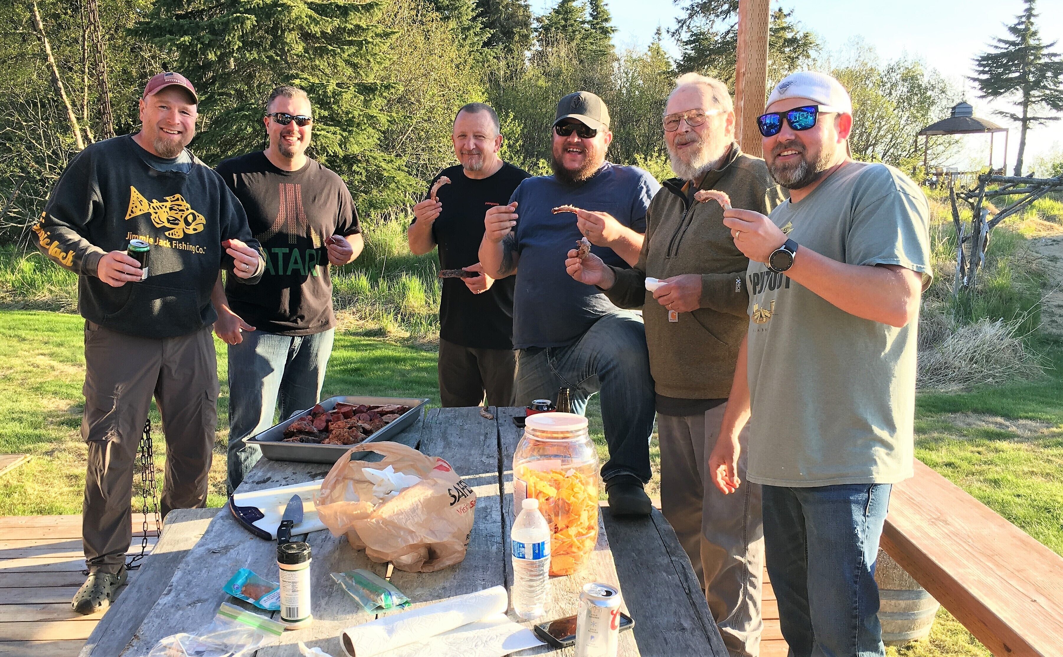 A group of people outdoors with a barbecue setup on a wooden deck.