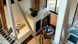 Un interior moderno con chimenea, una mesita y vistas al exterior a través de un ventanal.