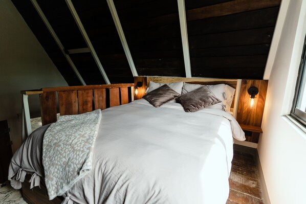 A bed with a wooden headboard, two bedside lamps, and a window on the right. - EyB Chalets (Ángeles)