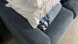 Ein graues Sofa mit einem weißen Kissen und einer gestreiften Decke.