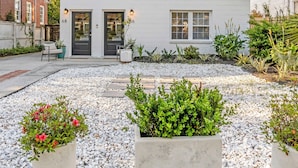 Et toetagers hus med en veranda, en indkørsel og en have med plantekasser.