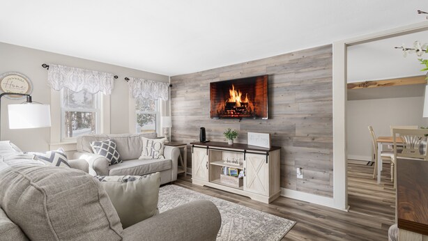 Una sala de estar con chimenea, un sofá, una mesa de centro y un comedor con una mesa y sillas.